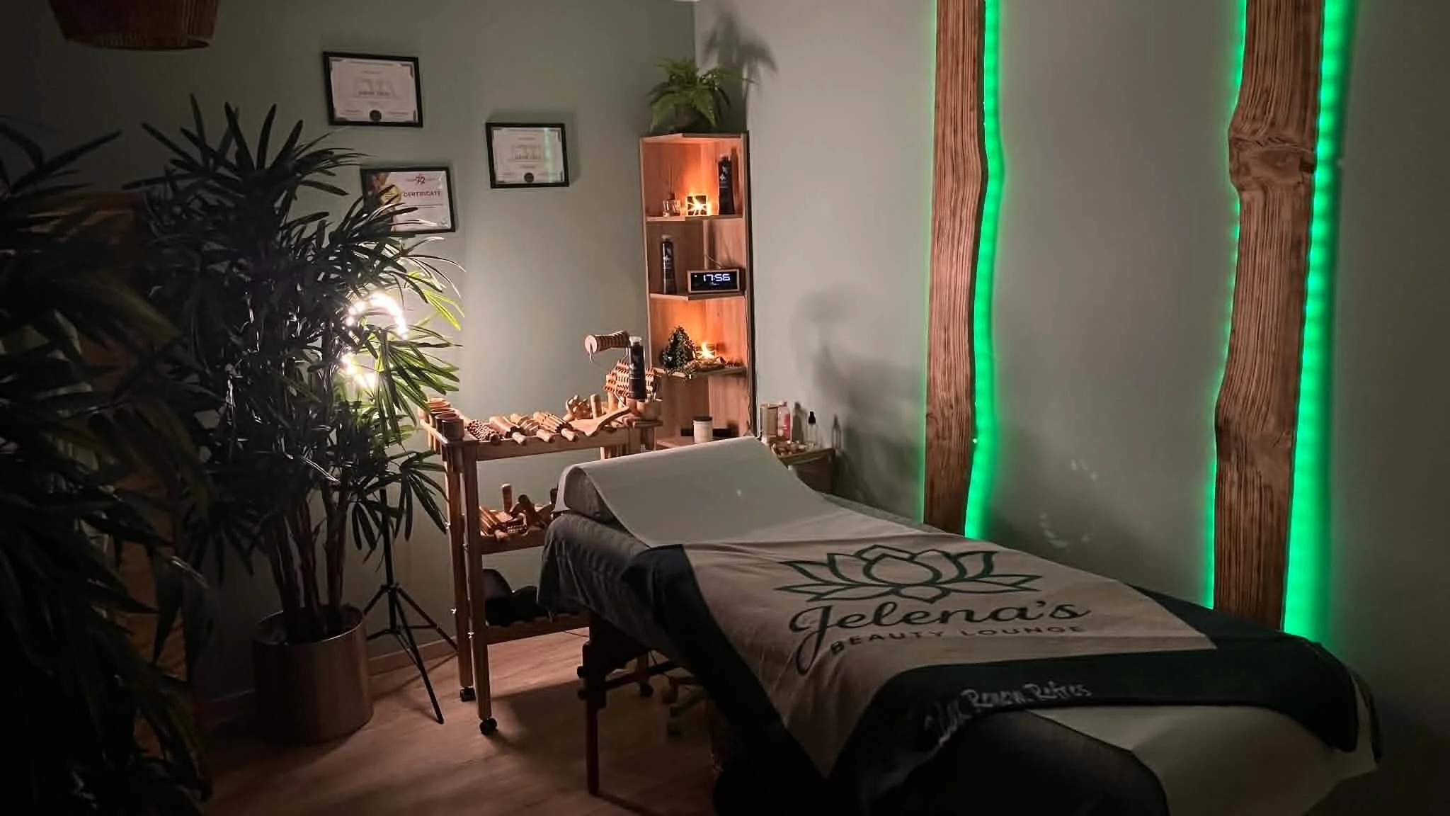 Behandlungsraum von Jelena's Beauty Lounge in Leiblfing – Massageliege mit Logo-Decke, Holzelemente und stimmungsvolles Licht
